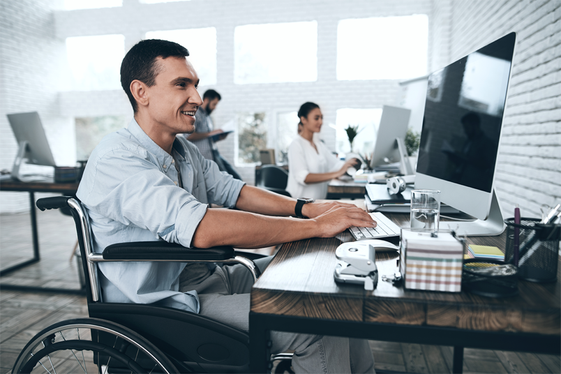 Man in wheelchair typing on keyboard depicting a Young Professional at work